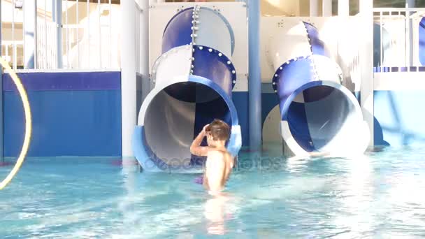 Der kleine Junge übt im Becken mit Wasserrutschen. 4k — Stockvideo