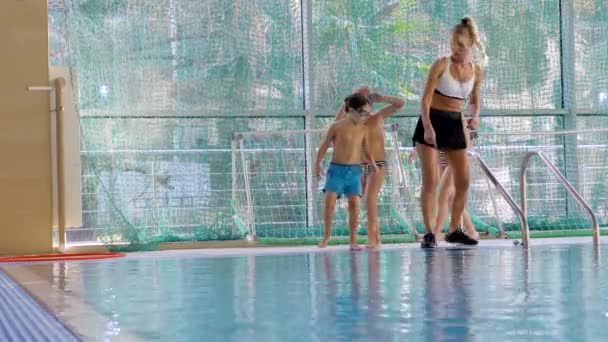 Девочка, тренер по плаванию, проводит тренировки в бассейне с детьми. 4k, slow motion — стоковое видео