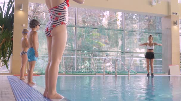 Девочка, тренер по плаванию, проводит тренировки в бассейне с детьми. 4k, slow motion — стоковое видео