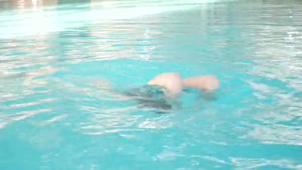 Dzieci pływać w basenie, dziewczyna sprawia, że rolki w wodzie 4k — Wideo stockowe