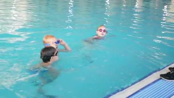 Het meisje, de coach van zwemmen, voert training in het zwembad met de kinderen. 4k, slow-motion — Stockvideo