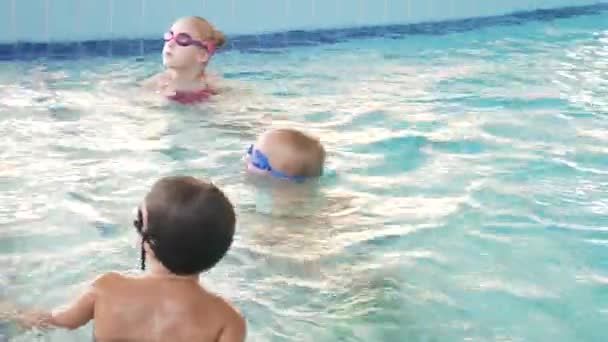 游泳教练在游泳池里和孩子们一起训练。4k、慢动作 — 图库视频影像