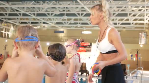 Het meisje, de coach van zwemmen, voert training in het zwembad met de kinderen. 4k, slow-motion — Stockvideo