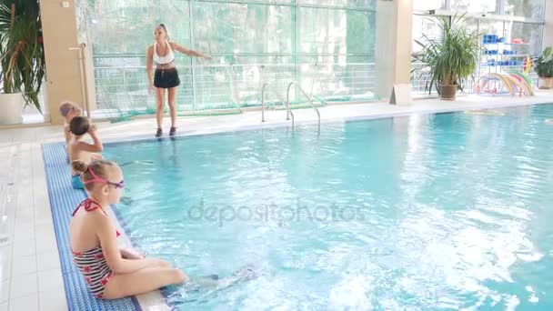 Das Mädchen, die Schwimmtrainerin, trainiert mit den Kindern im Pool. 4k, Zeitlupe — Stockvideo