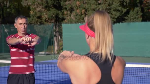 Los jugadores se calientan antes de un partido de tenis. Hombre y mujer mayores jugando tenis. 4k — Vídeos de Stock