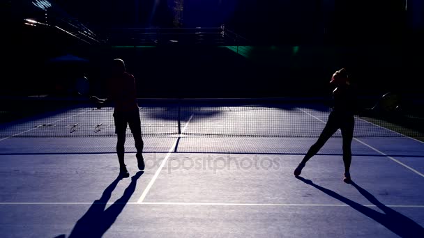 Los jugadores se calientan antes de un partido de tenis. Hombre y mujer mayores jugando tenis. 4k, siluetas — Vídeo de stock