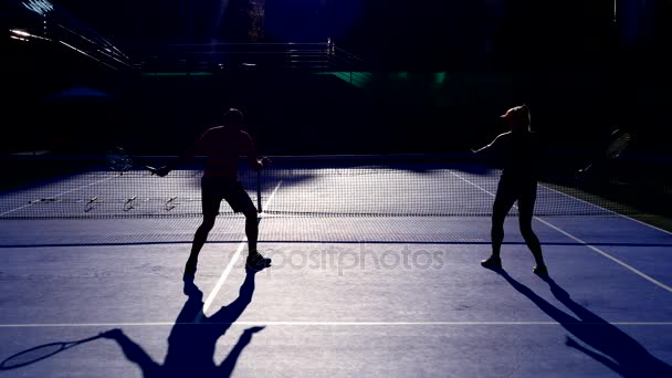 Hráči se zahřát před zahrát tenis. Starší muž a žena hrát tenis. 4k, siluety — Stock video