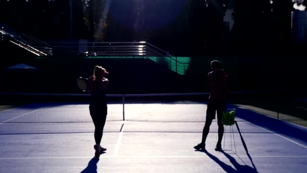 Spelers warming-up vóór een spel tennis. Senior man en vrouw tennissen. 4k, silhouetten — Stockvideo