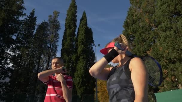 Los jugadores se calientan antes de un partido de tenis. Hombre y mujer mayores jugando tenis. 4k — Vídeos de Stock