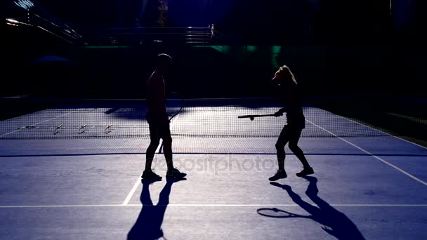 Ζέσταμα πριν από ένα παιχνίδι τένις παίκτες. Ανώτερος άνθρωπος και γυναίκα παίζει τένις. 4k, σιλουέτες — Αρχείο Βίντεο