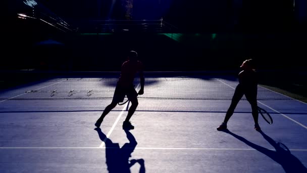 Players warm up before a game of tennis. Senior man and woman playing tennis. 4k, silhouettes — Stock Video