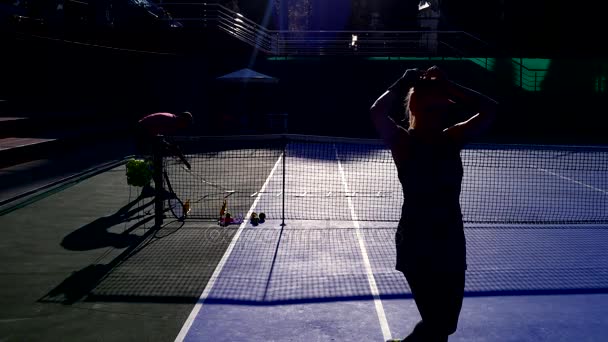 Les joueurs se réchauffent avant un match de tennis. Homme et femme âgés jouant au tennis. 4k, silhouettes — Video