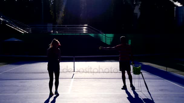 Los jugadores se calientan antes de un partido de tenis. Hombre y mujer mayores jugando tenis. 4k, siluetas — Vídeo de stock