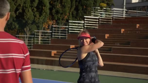 Jogadores aquecer antes de um jogo de tênis. Homem e mulher mais velhos a jogar ténis. 4k — Vídeo de Stock