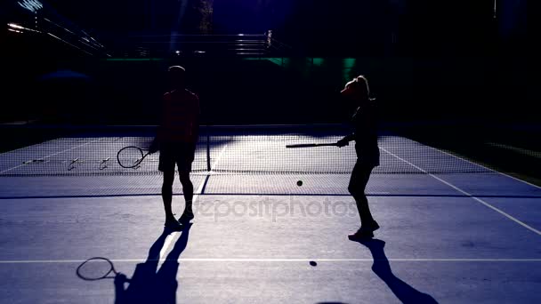 選手は、テニスの試合前にウォーム アップ。年配の男性と女性のテニスします。4 k、シルエット — ストック動画