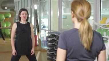 Bir kadın eğitmen portresi. yakın çekim. spor salonunda, 4 k germe egzersizleri fitness eğitmeni gösterir.