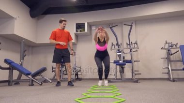 Genç Yetişkin kız onu kişisel antrenörü tarafından liderliğindeki simülatörleri bir egzersiz yapıyor. 4k, ağır çekim