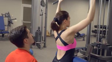 Genç Yetişkin kız onu kişisel antrenörü tarafından liderliğindeki simülatörleri bir egzersiz yapıyor. 4k, ağır çekim