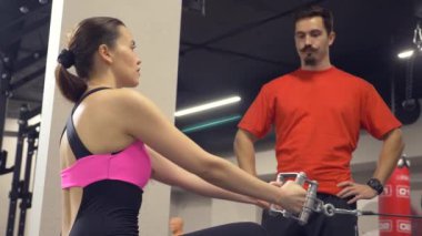 Genç Yetişkin kız onu kişisel antrenörü tarafından liderliğindeki simülatörleri bir egzersiz yapıyor. 4k, ağır çekim