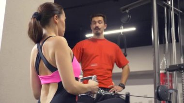 Genç Yetişkin kız onu kişisel antrenörü tarafından liderliğindeki simülatörleri bir egzersiz yapıyor. 4k, ağır çekim