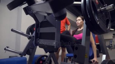 Genç Yetişkin kız onu kişisel antrenörü tarafından liderliğindeki simülatörleri bir egzersiz yapıyor. 4k, ağır çekim