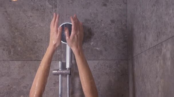 Женщина принимает душ. Замедление. красивая девушка наслаждается водой. Она подняла руки и вода упала ей на ладонь. 4k — стоковое видео