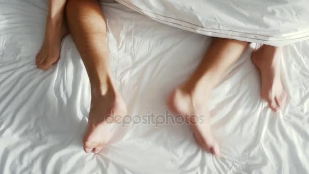 Pár v posteli milování. mužské a ženské nohy shora, bílým ložním prádlem. sex, 4k — Stock video