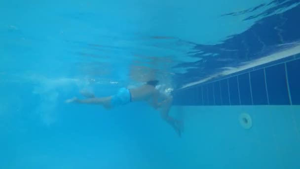 I bambini stanno nuotando in piscina, il ragazzo sta facendo un rotolo in acqua. 4k tiro sott'acqua — Video Stock