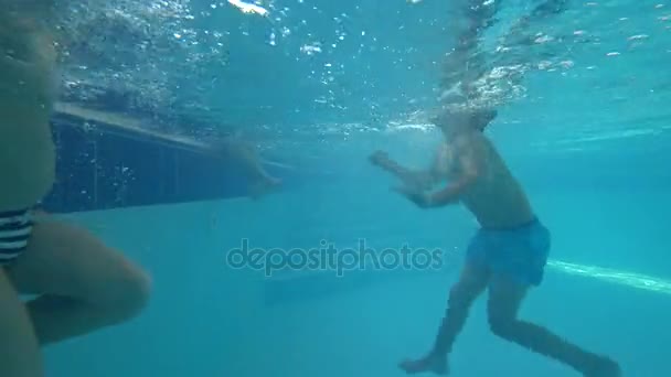 Kinder schwimmen im Pool, der Junge macht eine Rolle im Wasser. 4k Schießen unter Wasser — Stockvideo