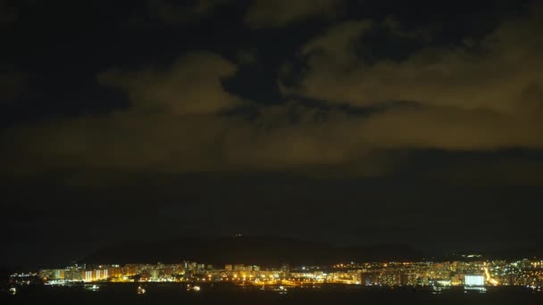 Ciudad portuaria nocturna con nubes voladoras sobre ella, pintada por la luz nocturna de la ciudad. 4k. lapso de tiempo. Cronograma . — Vídeo de stock