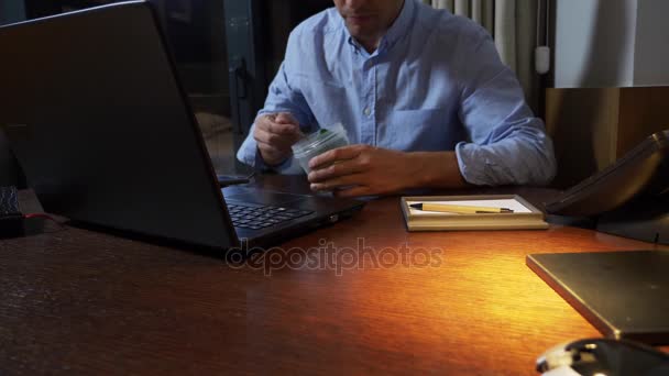 Un uomo mangia broccoli da un contenitore di cibo, lavorando su un computer portatile, a tarda notte, cibo sano, dieta. 4k . — Video Stock