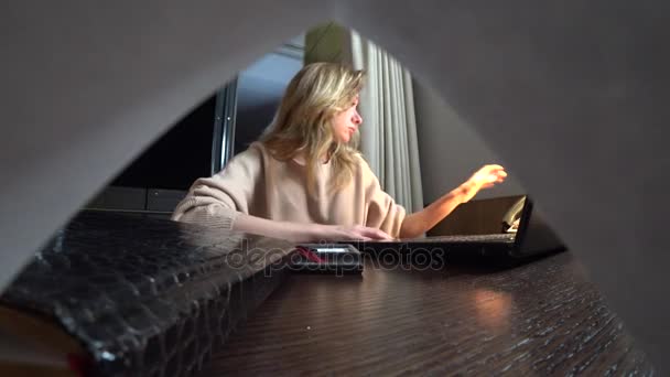 Женщина, работающая на ноутбуке за столом ночью в номере отеля. 4k. Она засыпает на рабочем месте, телефонный звонок будит ее  .. — стоковое видео