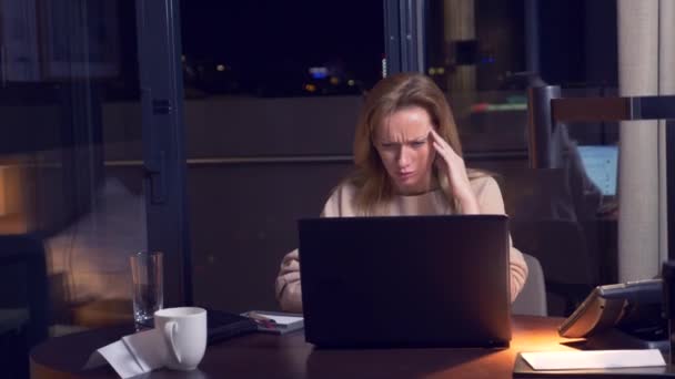 Mujer trabajando en un portátil en una mesa por la noche en una habitación de hotel. 4k. se duerme en el lugar de trabajo, bosteza . — Vídeos de Stock