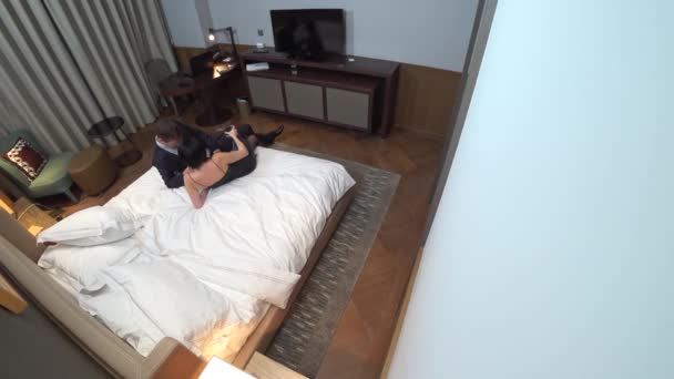 Couple, homme d'affaires et femme brune aux cheveux courts embrassant sur le lit dans la chambre d'hôtel. 4k. le concept de trahison, prostitution, harcèlement sexuel. caméra de surveillance cachée. compromettant — Video