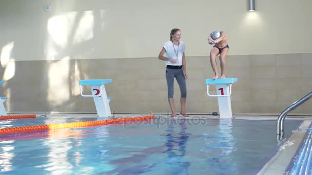 Entrenamiento de atleta de natación. El entrenador le enseña al niño a sumergirse en la piscina deportiva. 4k, cámara lenta — Vídeo de stock
