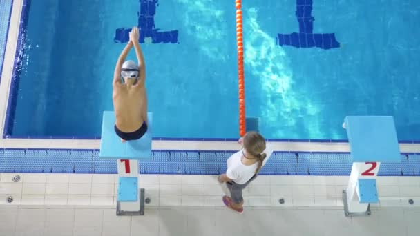 Entraînement d'athlète de natation. Le coach apprend au garçon à plonger dans la piscine sportive. 4k, au ralenti — Video