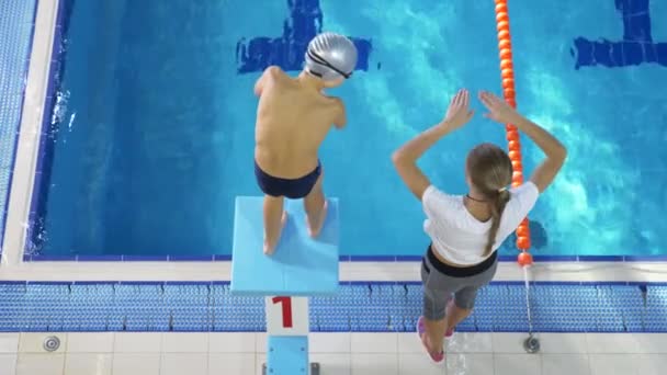 Zwemmen atleet opleiding. De coach leert de jongen om te duiken in het zwembad van de sport. 4k, slow-motion — Stockvideo