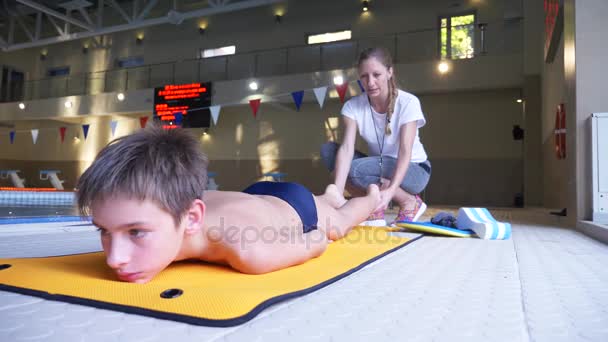 Treino de atleta de natação. O treinador ensina o menino a mergulhar na piscina esportiva. 4k, câmera lenta — Vídeo de Stock