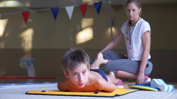 Тренировка по плаванию. Тренер учит мальчика нырять в спортивный бассейн. 4k, slow motion — стоковое видео