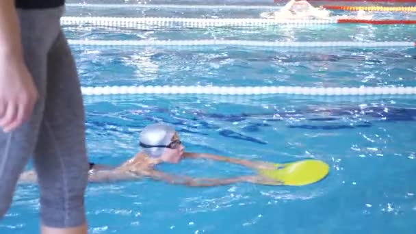 Úszni sportoló képzés. Az edző azt tanítja, hogy a fiút, hogy belevetik magukat a sport-medence. 4k, lassú mozgás — Stock videók