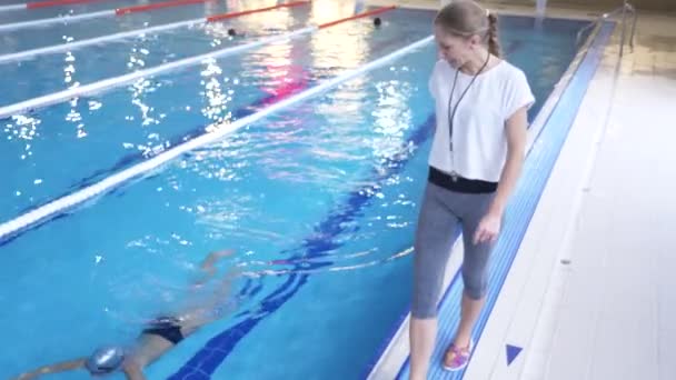 Úszni sportoló képzés. Az edző azt tanítja, hogy a fiút, hogy belevetik magukat a sport-medence. 4k, lassú mozgás — Stock videók