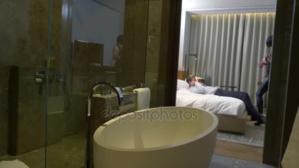 Paar, männlicher Geschäftsmann und brünette Frau mit kurzen Haaren in Lederhose und Schwertgürtel benutzen Peitsche und Handschellen zu sexuellen Zwecken auf dem Bett in einem Hotelzimmer. 4k — Stockvideo