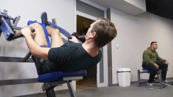 4k ist ein lustiger Mensch ohne Trainer im Fitnessstudio an den Simulatoren beschäftigt. Er macht die Übungen nicht richtig. Ausraster in der Turnhalle — Stockvideo