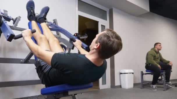 4k, a funny person is engaged in the gym on the simulators without a coach. he does not do the exercises correctly. freak in the gym — Stock Video
