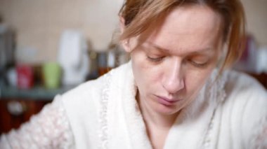 bir sabahlık soluk bir kadında masada yiyor. o bir yorgun vardır. 4k, arka plan bulanıklık. yakın çekim