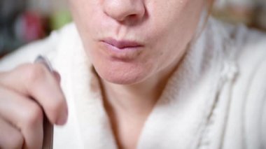 bir sabahlık soluk bir kadında masada yiyor. o bir yorgun vardır. 4k, arka plan bulanıklık. yakın çekim