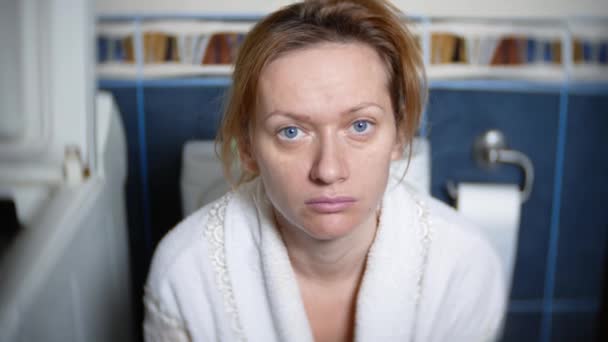 Портрет. бледная женщина сидит в туалете на унитазе. 4k, размытый фон . — стоковое видео