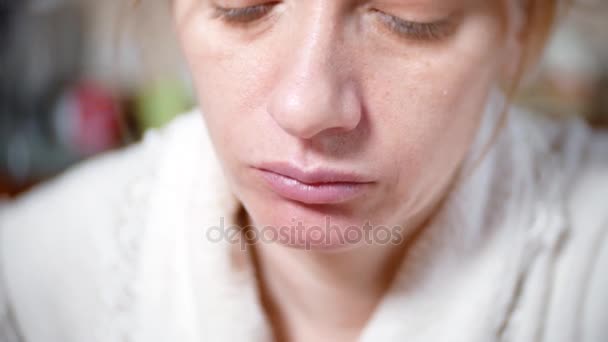 A pale woman in a dressing gown is eating at the table. she has a tired. 4k, background blur. close-up — Stock Video