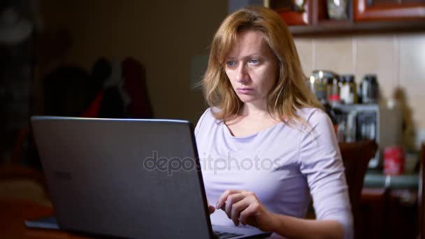 A woman in a bathrobe and with wet hair sitting at home on the couch, watching changes in the currency exchange chart, looking at the computer monitor, freelancing, 4k, blurring the background — Stock Video