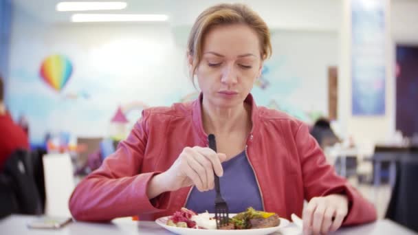 Женщина, которая ест жареные овощи и шашлык в кафе. 4К, размыть фон. место для копирования — стоковое видео